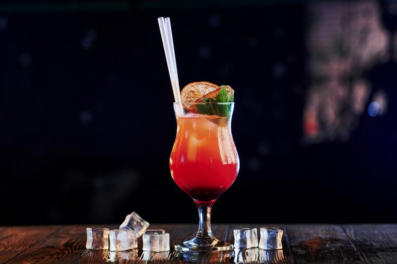 Roter Cocktail im Glas vor dunklem Hintergrund.