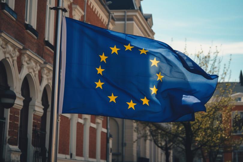 EU-Flagge weht im Wind vor einem Gebäude.